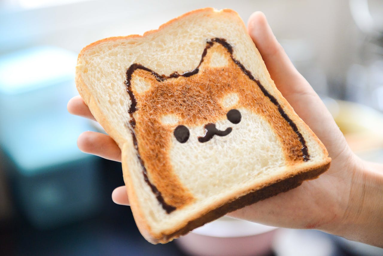 Adorable Shiba Inu face toast art, perfect for breakfast fun, held by hand in a bright setting.